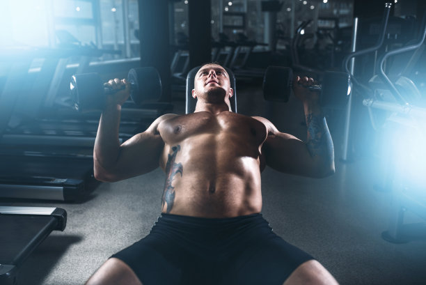 男健美运动员在健身房用哑铃训练图片下载