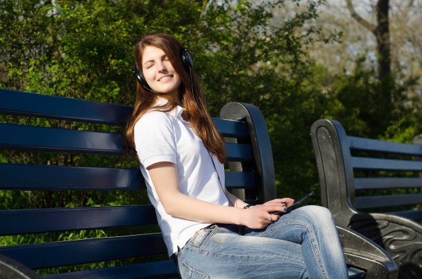 少女戴着耳机坐在长椅上听音乐图片下载