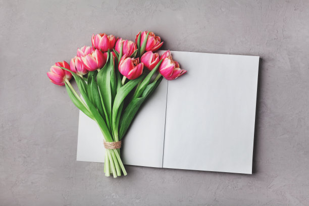 打开空笔记本，里面放着一束粉红色的郁金香花。女人工作的办公桌。平的。图片下载