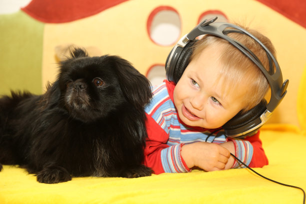 一个带着狗戴着耳机听音乐的有趣孩子图片下载