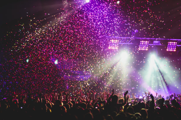 观看摇滚音乐会在大音乐厅演出，伴着人群和舞台灯光，拥挤的音乐厅伴着现场灯光，摇滚表演表演，伴着人们剪影素材图片