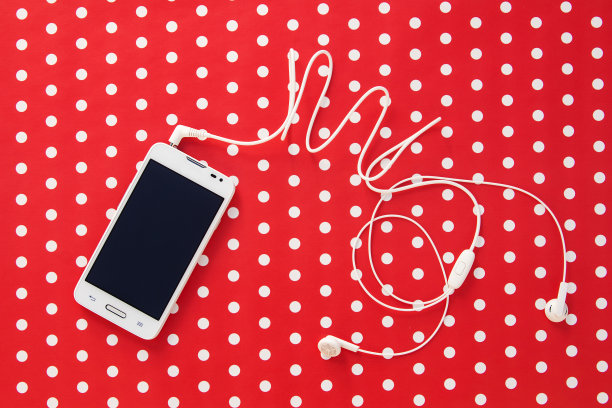 小耳机与手机在红纸上点图片下载