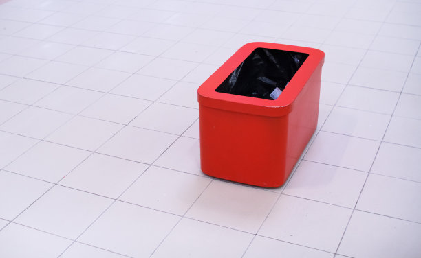 红色垃圾桶，垃圾桶被隔离在白色的路径上图片下载