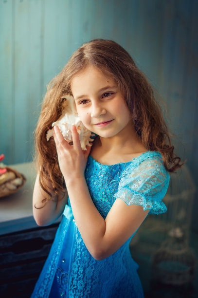 穿着蓝色衣服的女孩听着贝壳的声音图片下载