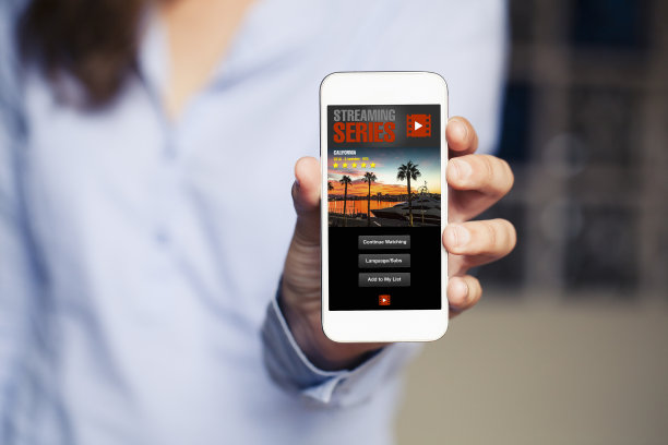 女人手里拿着手机，屏幕上显示着流媒体视频应用程序。素材图片