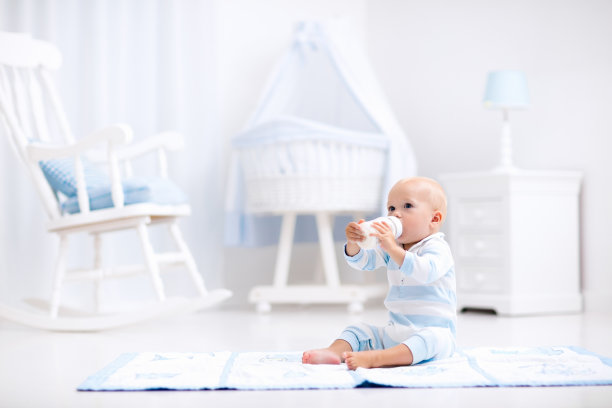 男婴在阳光明媚的托儿所喝牛奶素材图片