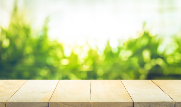 木制桌面模糊的绿色花园在早上的背景。图片下载