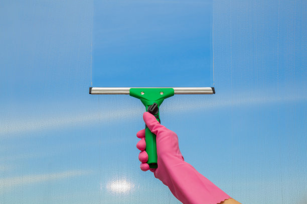 手戴手套，用专业清洁刷清洗窗户。素材图片