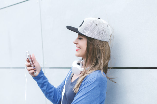 年轻女子的肖像戴着耳机和手机。图片下载