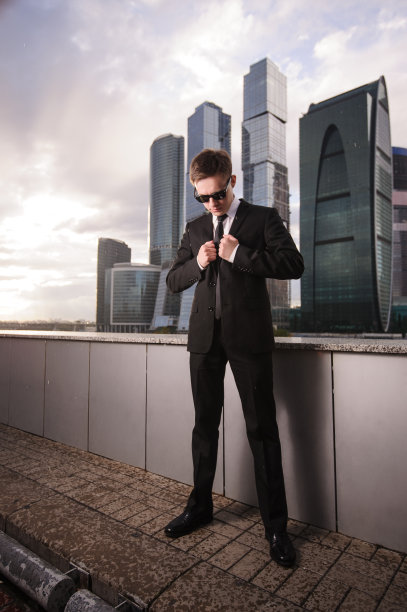 商人在摩天大楼的背景上扣上他的夹克图片下载