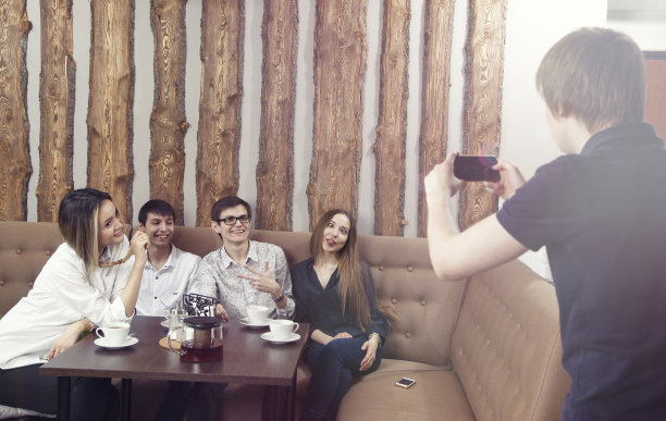 一名男子用智能手机拍下了一群年轻人的照片，包括两对男女，他们正在咖啡馆喝咖啡图片下载