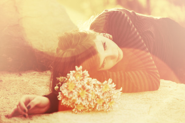 一个悲伤的年轻女子，她的墓碑上躺着一朵花图片下载