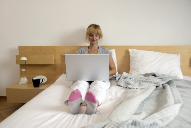 女商人躺在床上用着笔记本电脑图片下载