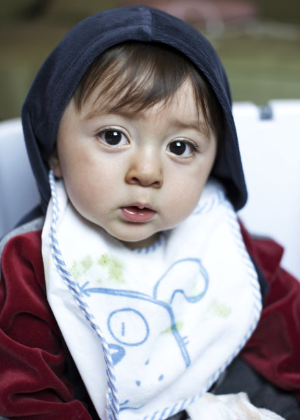 这是一幅悲伤严肃的多种族亚裔白种人小男孩的肖像，他有着棕色的大眼睛，穿着蓝色和栗色的羊毛夹克和白色围嘴图片下载