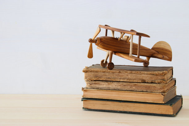 旧书旁边的飞机玩具放在木桌上图片下载