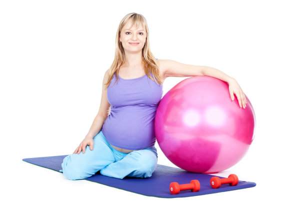 年轻孕妇在健身垫子上用健身球休息图片下载
