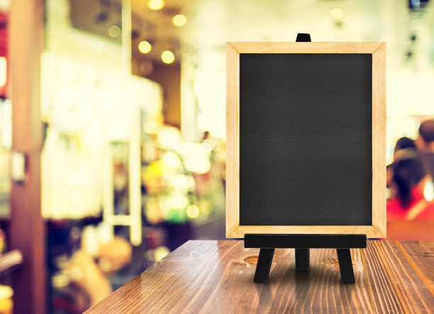 模糊的咖啡店背景木桌上的带有画架的黑板，模拟展示或蒙太奇设计用于网上购物促销素材图片