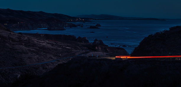 夜晚，海滩小镇附近道路上的车灯图片下载