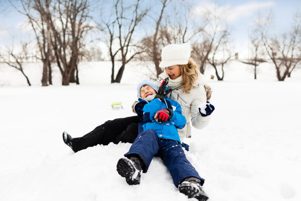 小男孩和他的妈妈在雪地上玩图片下载
