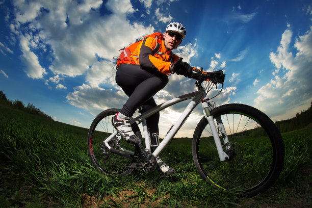 一个年轻人背着背包骑着自行车穿过深草丛图片下载