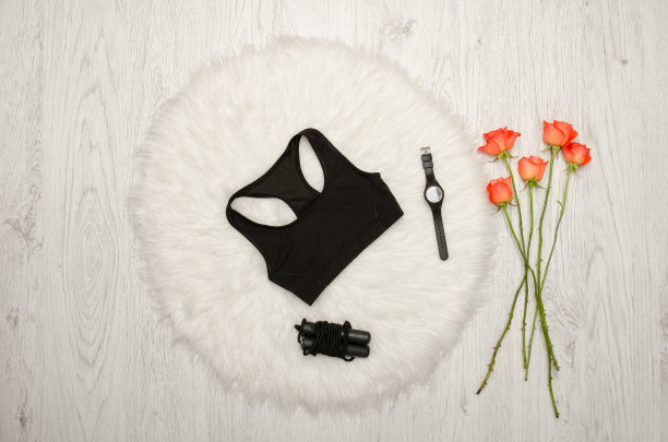 黑色运动上衣，观看和跳绳。木制背景上的橙色玫瑰。时尚概念，俯视图图片下载