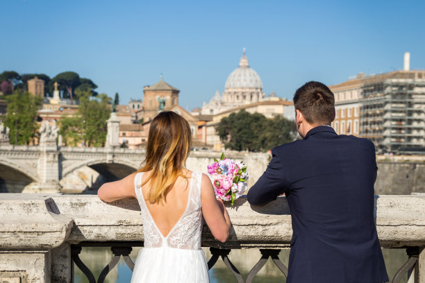 新郎和新娘在台伯河岸边拍摄婚礼照片，意大利罗马圣彼得大教堂图片下载