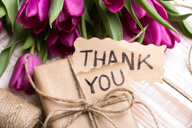 “谢谢”卡片、礼盒和白色木质背景的郁金香花束图片下载