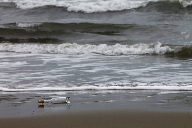 岸边的空瓶子，身后是波浪图片下载