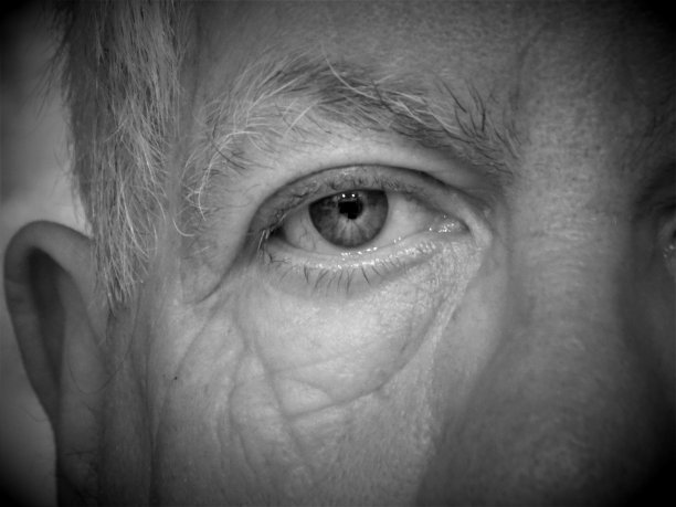 时间雕刻了许多著名的年龄线和皱纹上这个老人的脸- B&W近距离的一个人的眼睛图片下载