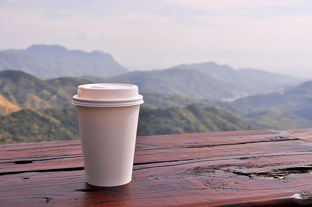 白色杯子里的咖啡，背后是自然风景。图片下载