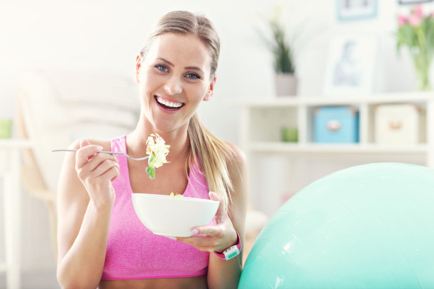 年轻女子在锻炼后吃健康的沙拉图片下载