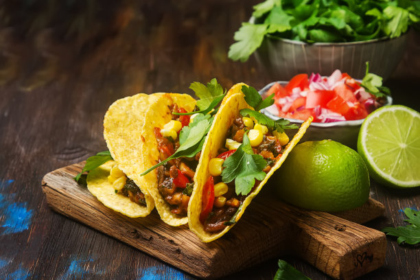 传统的墨西哥玉米饼配西红柿，肉，香草。黑暗的背景。快餐。图片下载