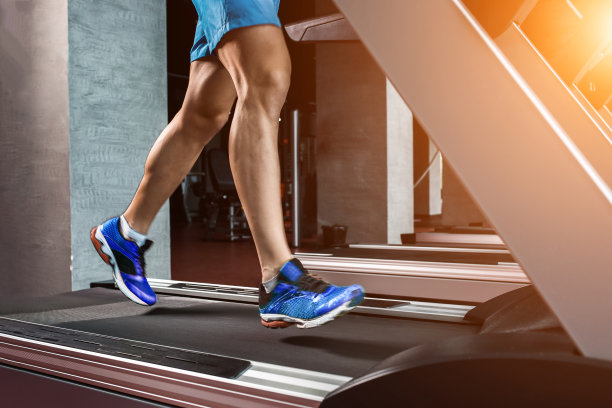 侧视图全长度的年轻男子在运动服跑步机上在健身房图片下载