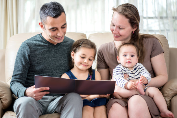 幸福的全家福。母亲和父亲与两个女儿一起读书和享受时间。图片下载