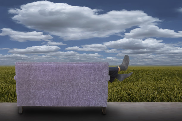 一个男人躺在一大片空地上的白色沙发上图片下载