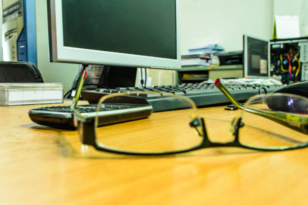 一个玻璃杯和一个工作装置放在木桌上。图片下载