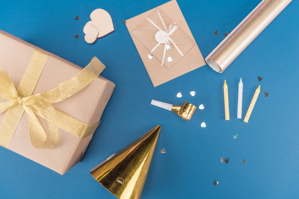 顶视图的礼盒，蜡烛，生日帽和信封孤立在蓝色，生日派对的概念图片下载
