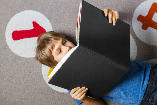 小男孩在家里的地板上看书图片下载