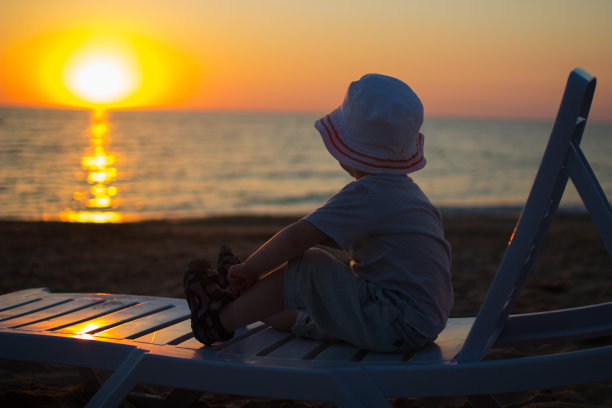 婴儿坐在沙滩上的躺椅上图片下载