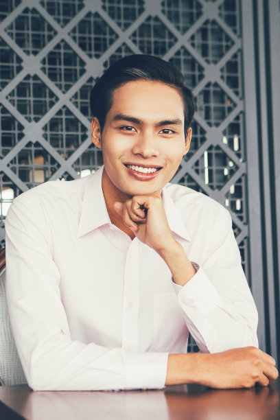 微笑的年轻亚洲男子坐在餐厅图片下载