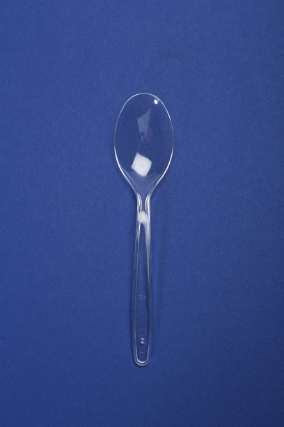 蓝色纸背景上的透明塑料勺。快餐的概念图片下载