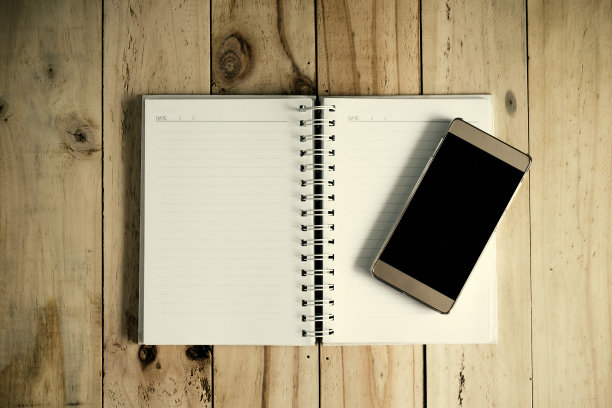 笔记本和智能手机放在木桌上。前视图。图片下载