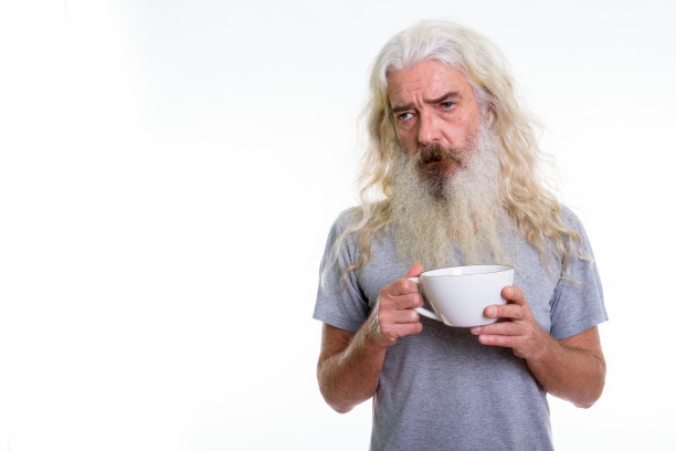 照片中，满脸胡须的年长男子手拿咖啡杯，看起来很疲惫图片下载