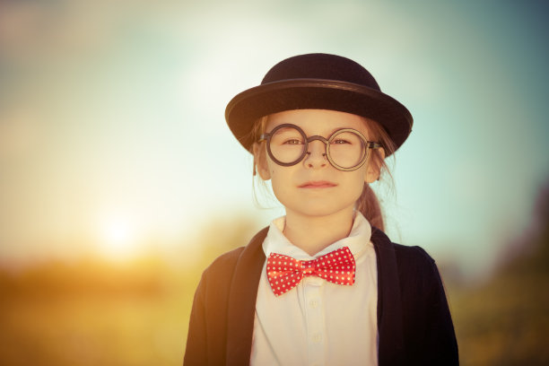 戴着蝴蝶结和圆顶礼帽的有趣小女孩。图片下载