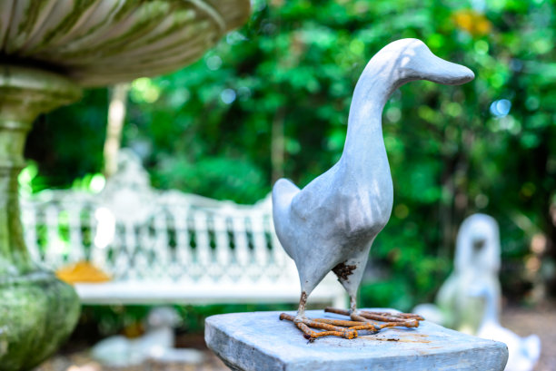 鸭子雕像装饰在花园模糊的背景图片下载