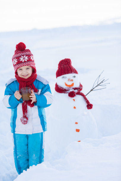 快乐美丽的孩子在花园里堆雪人，冬天的时候，h图片下载