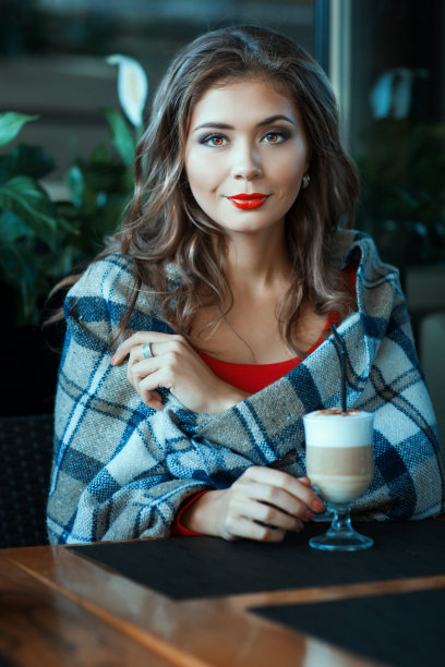 美丽的女孩坐在毯子里，旁边是咖啡。图片下载