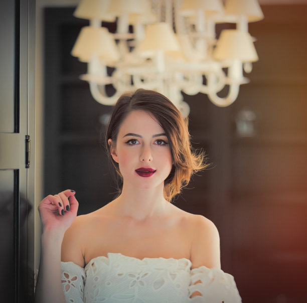 美丽的年轻女子站在门口在灯光豪华的房间图片下载