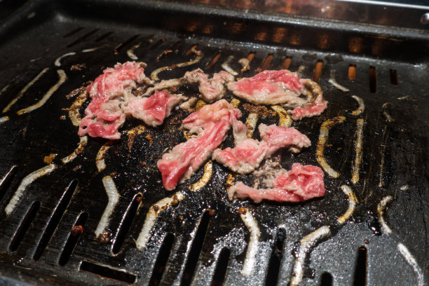 烤盘上烤制的红色牛肉片图片下载