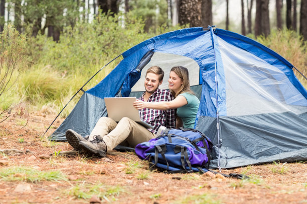 年轻漂亮的徒步夫妇坐在帐篷里看笔记本电脑素材图片
